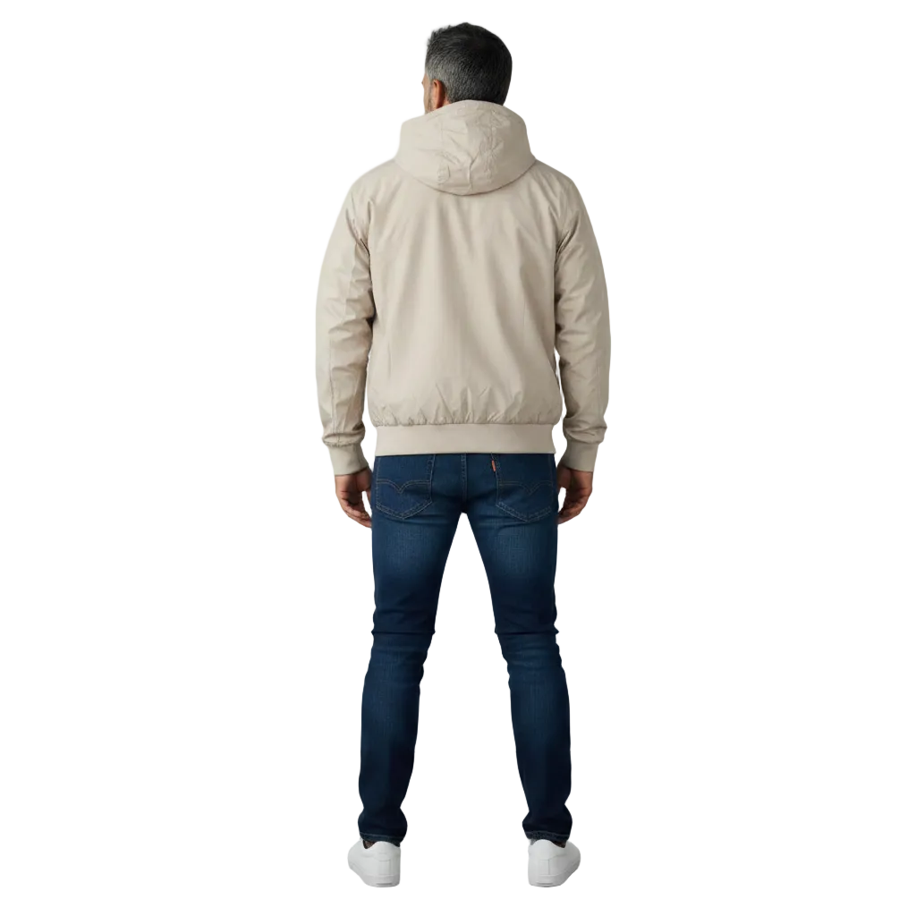 A man viewed from behind wearing a light beige hooded jacket, dark blue jeans, and white sneakers, standing against a plain light gray studio background.