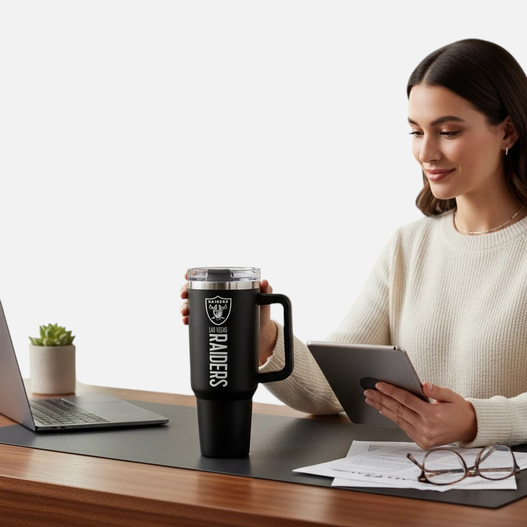 Coliseum Sports Las Vegas Raiders 40 oz black stainless steel tumbler with flip straw held by a woman at a desk