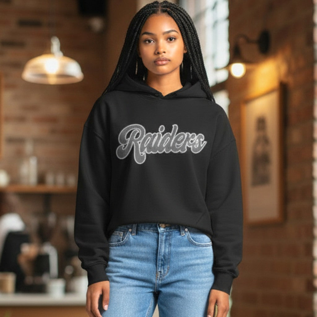 Coliseum Sports women's black cropped Las Vegas Raiders pullover hoodie with script logo worn by a model